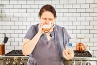 A person drinks a glass of Bare Bones Bone Broth Instant Powdered Beverage Mix
