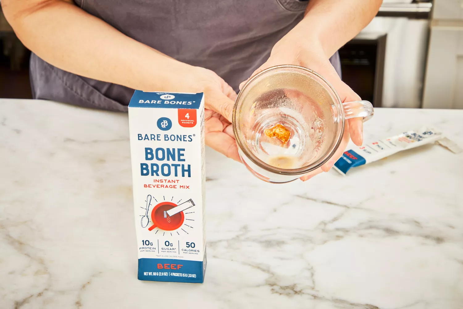 A person holds up a glass after drinking Bare Bones Bone Broth Instant Powdered Beverage Mix