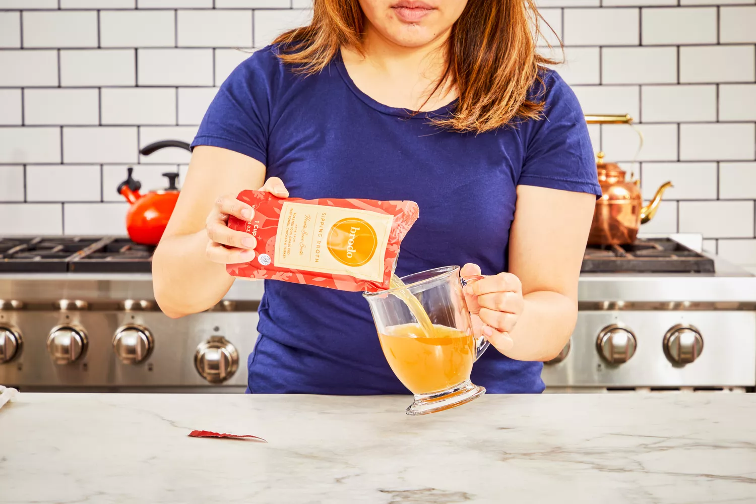 A person pours Brodo Hearth Bone Broth into a glass