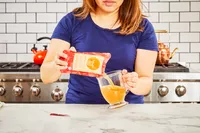 A person pours Brodo Hearth Bone Broth into a glass