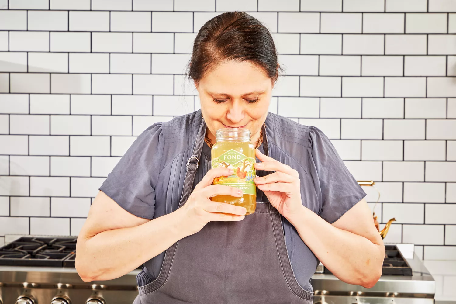 A person smells a jar of FOND Certified Organic Chicken Bone Broth