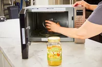 A person puts a glass of FOND Certified Organic Chicken Bone Broth in the microwave