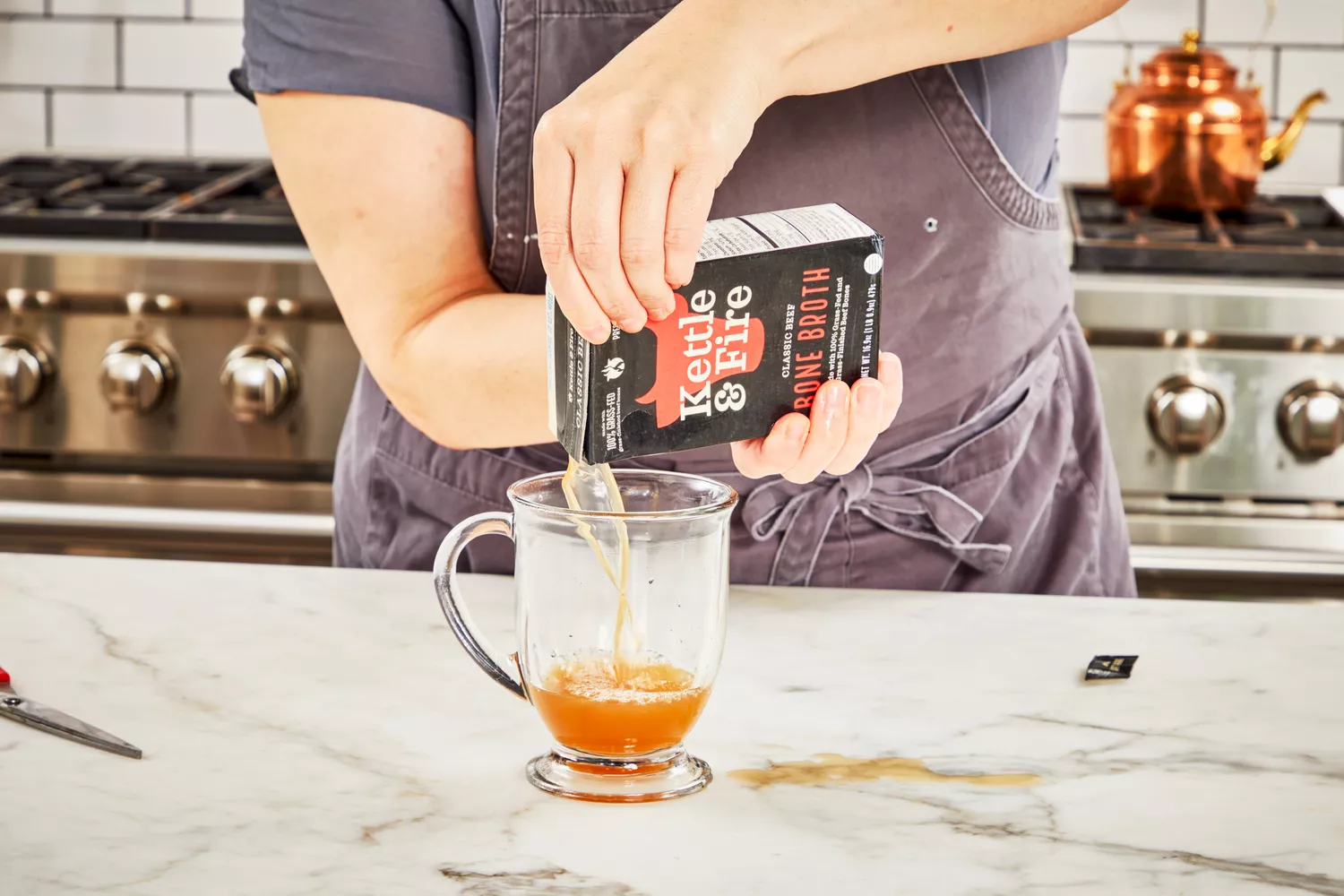 A person pours Kettle & Fire Bone Broth into a glass