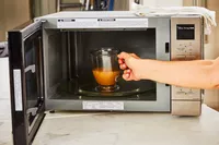 A glass of Pacific Foods Chicken Bone Broth is placed in a microwave
