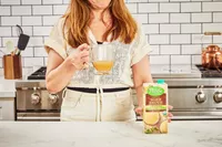 A person holds a glass of Pacific Foods Chicken Bone Broth