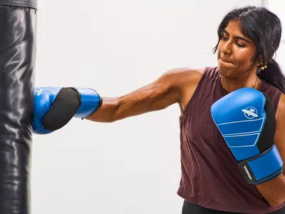 A person punches a bag while wearing the Hayabusa S4 Leather Boxing Gloves