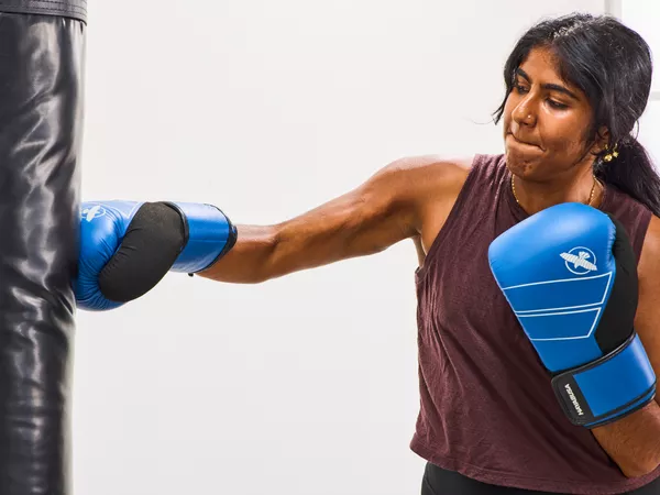 A person punches a bag while wearing the Hayabusa S4 Leather Boxing Gloves