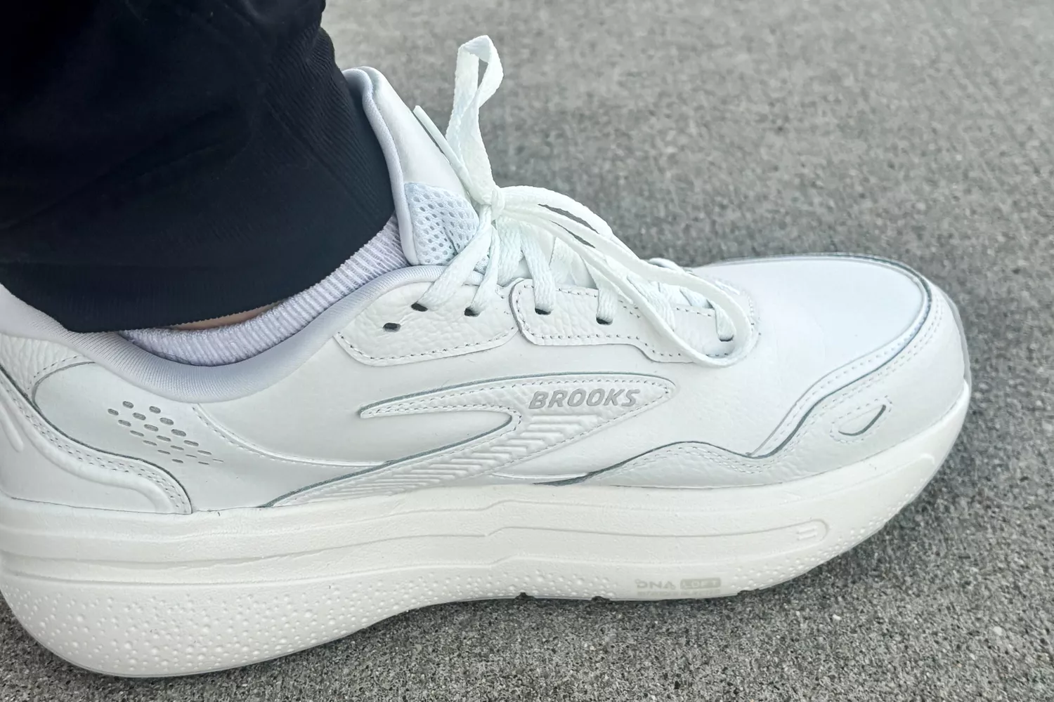 A close-up of a foot wearing the Brooks Men's Ghost Max L Sneaker on carpet