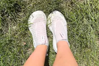 A person stands in grass while wearing the Brooks Women's Glycerin 22 SE Running Shoes
