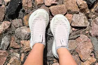 A person wears the Brooks Women's Glycerin 22 SE Running Shoes while standing on rocky ground