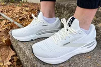 A person wears the Brooks Men's Adrenaline GTS 24 Running Shoes outside on stone