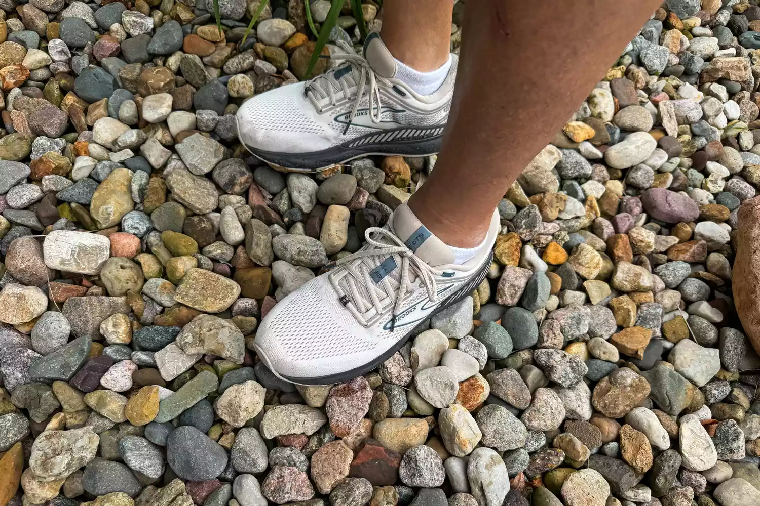 A person wears a pair of Brooks Men's Beast GTS 23 Running Shoe on small rocks