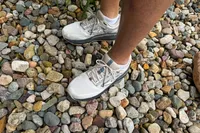 A person wears a pair of Brooks Men's Beast GTS 23 Running Shoe on small rocks