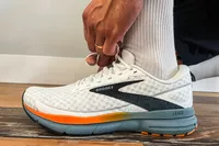 A person ties the laces on the Brooks Men's Trace 3 Road Running Shoes