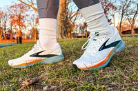 A person wears the Brooks Men's Trace 3 Road Running Shoes while walking through grass