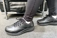 A close-up of a person wearing Brooks Women's Addiction Walker 2 Sneakers and leggings standing on a carpeted floor