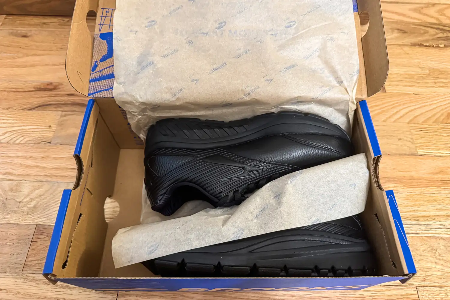 A pair of Women's Addiction Walker 2 Sneakers in a shoebox partially covered with wrapping paper