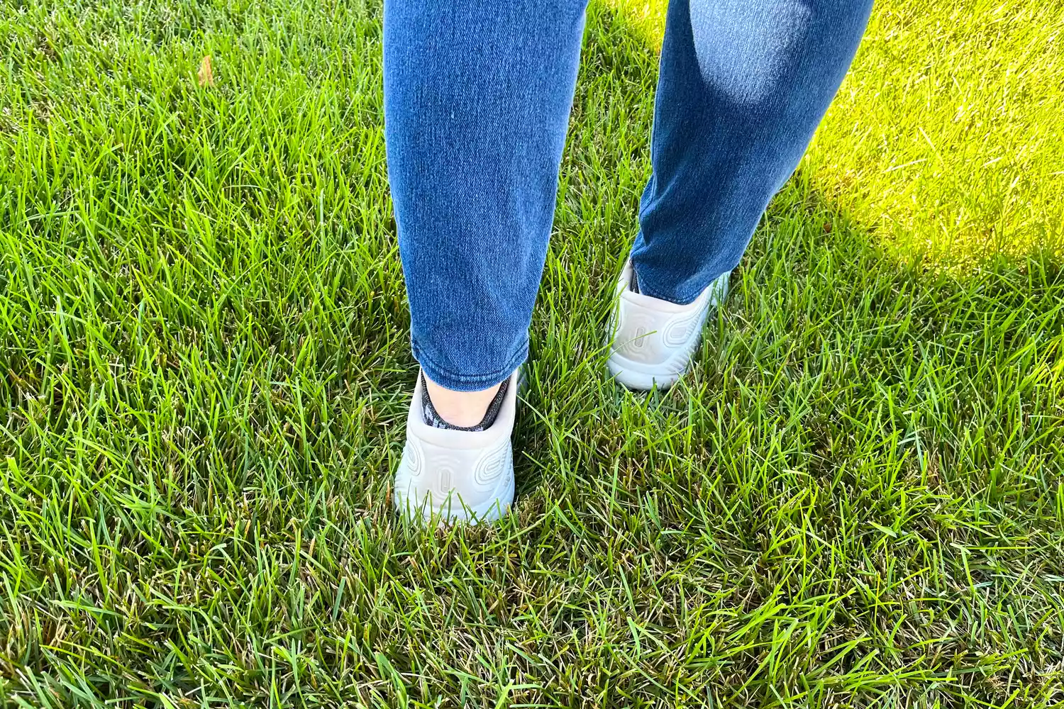 A person walks through grass while wearing the Brooks Women's Ariel GTS 23 Running Shoes