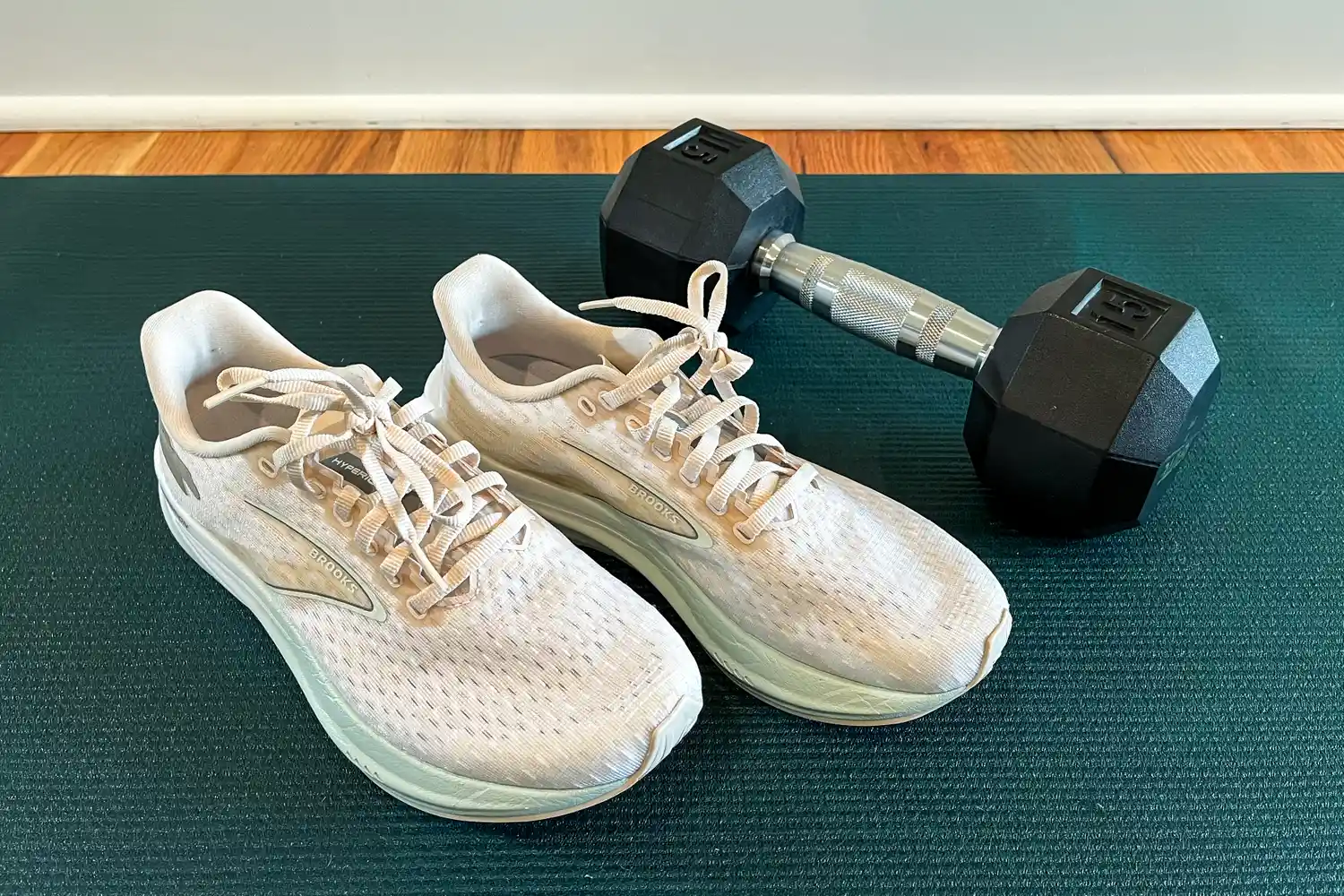 Running shoes next to a dumbbell on a workout mat