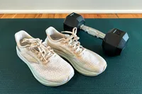 Running shoes next to a dumbbell on a workout mat