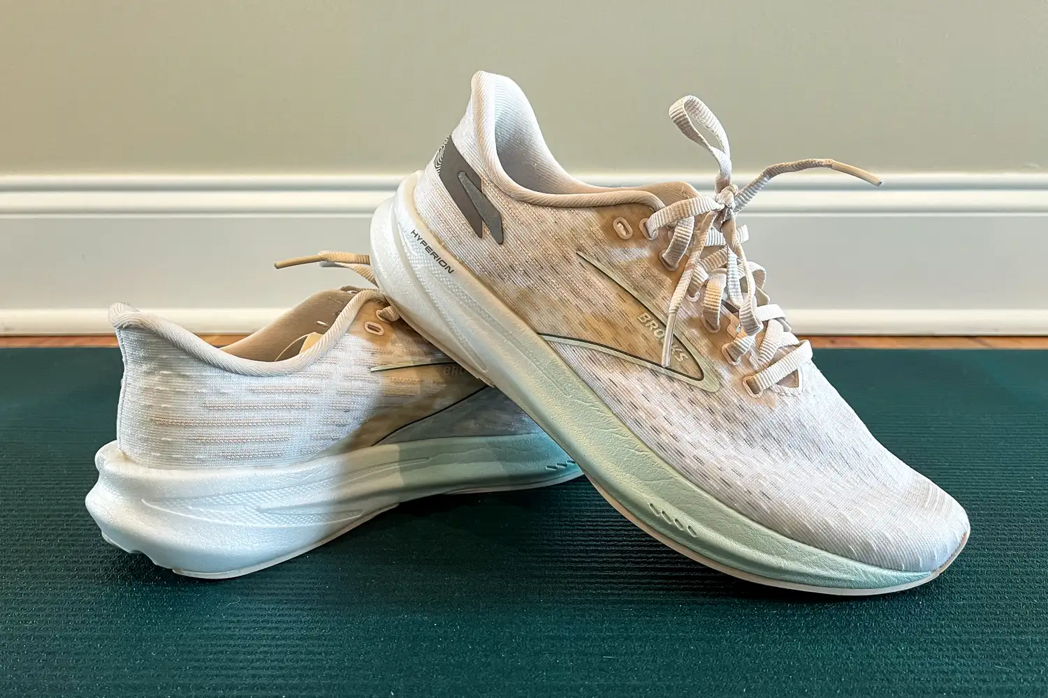 A pair of running shoes positioned on a mat with one shoe resting on the other, branding visible on the side of the shoe