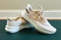 A pair of running shoes positioned on a mat with one shoe resting on the other, branding visible on the side of the shoe