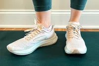 A pair of athletic shoes on feet, shown indoors on a mat