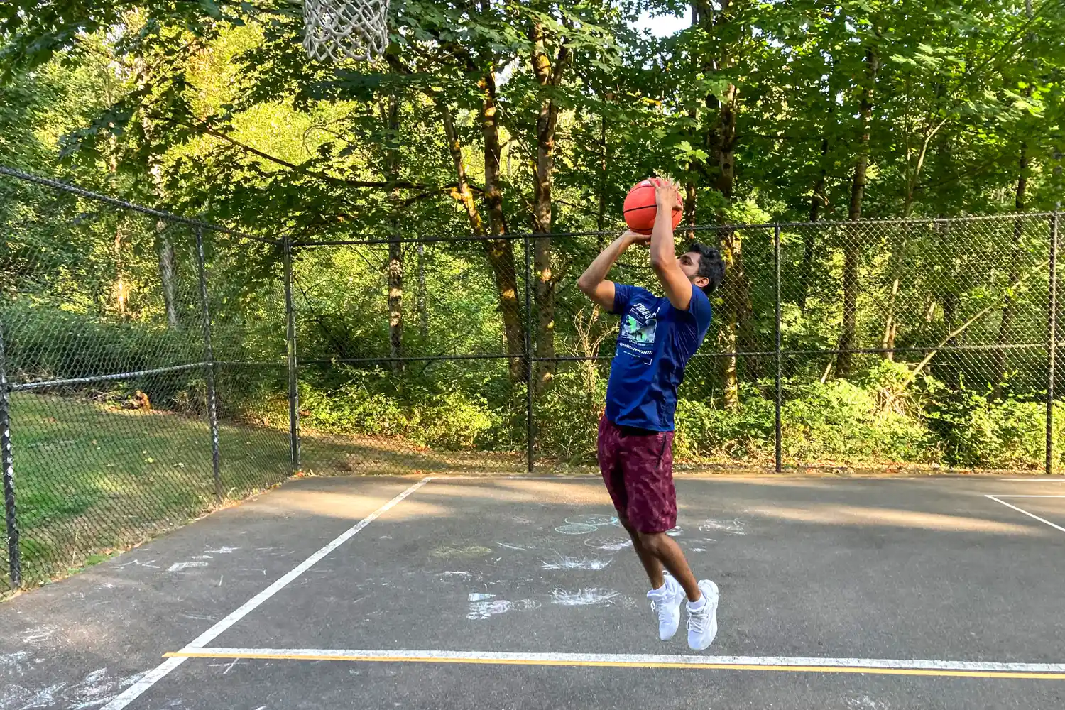 A person jumps while shooting the Champion Sports Pro Style Basketball