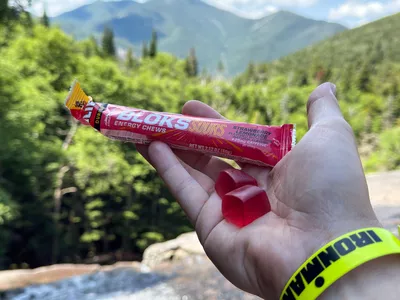 A person holds up Clif Bar Bloks Energy Chews in their hand while biking outside