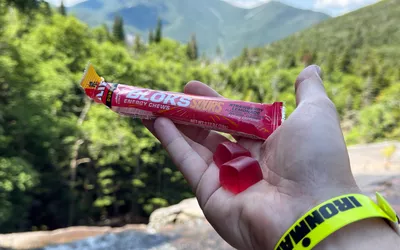 A person holds up Clif Bar Bloks Energy Chews in their hand while biking outside