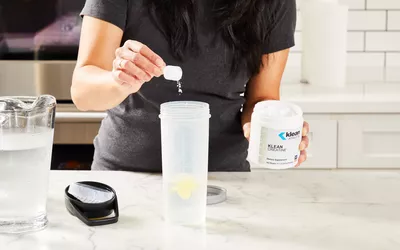 A person pours a scoop into Klean Athlete Klean Creatine
