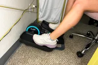 A person pedals the Cubii Move Under Desk Elliptical Bike