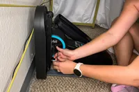 A person assembles the Cubii Move Under Desk Elliptical Bike