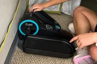 A person assembles the Cubii Move Under Desk Elliptical Bike