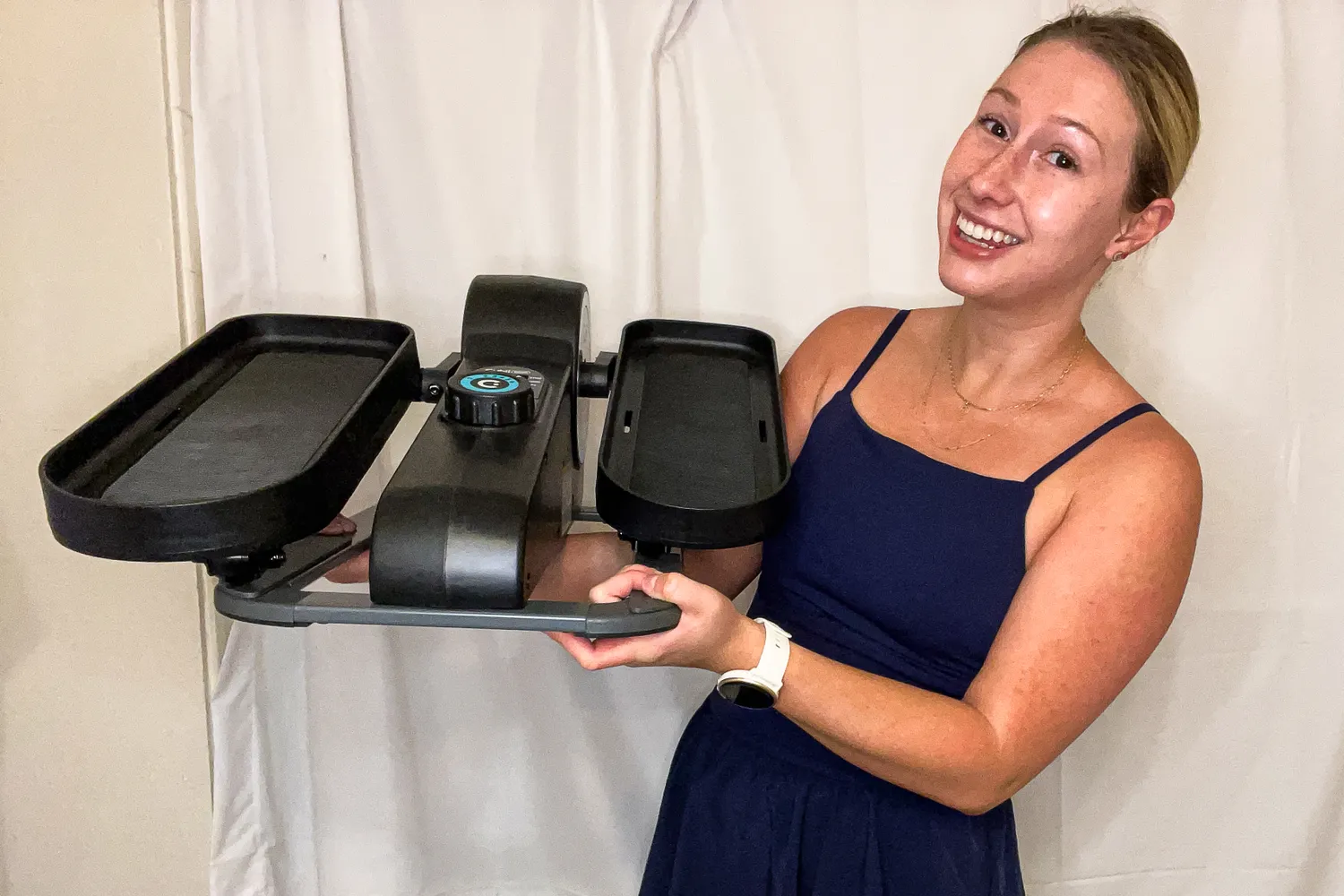 A person lifts the Cubii Move Under Desk Elliptical Bike