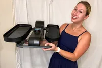 A person lifts the Cubii Move Under Desk Elliptical Bike