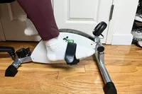 A person uses the DeskCycle 2 Under Desk Bike Pedal Exerciser