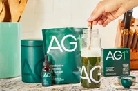 Person stirring AG1 by Athletic Greens in a glass