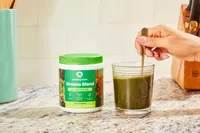 Person stirring glass of Amazing Grass Greens Blend Superfood