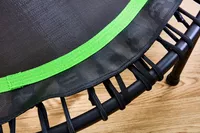 The BCAN 450/550 Lbs Foldable Mini Trampoline strings with a wooden background