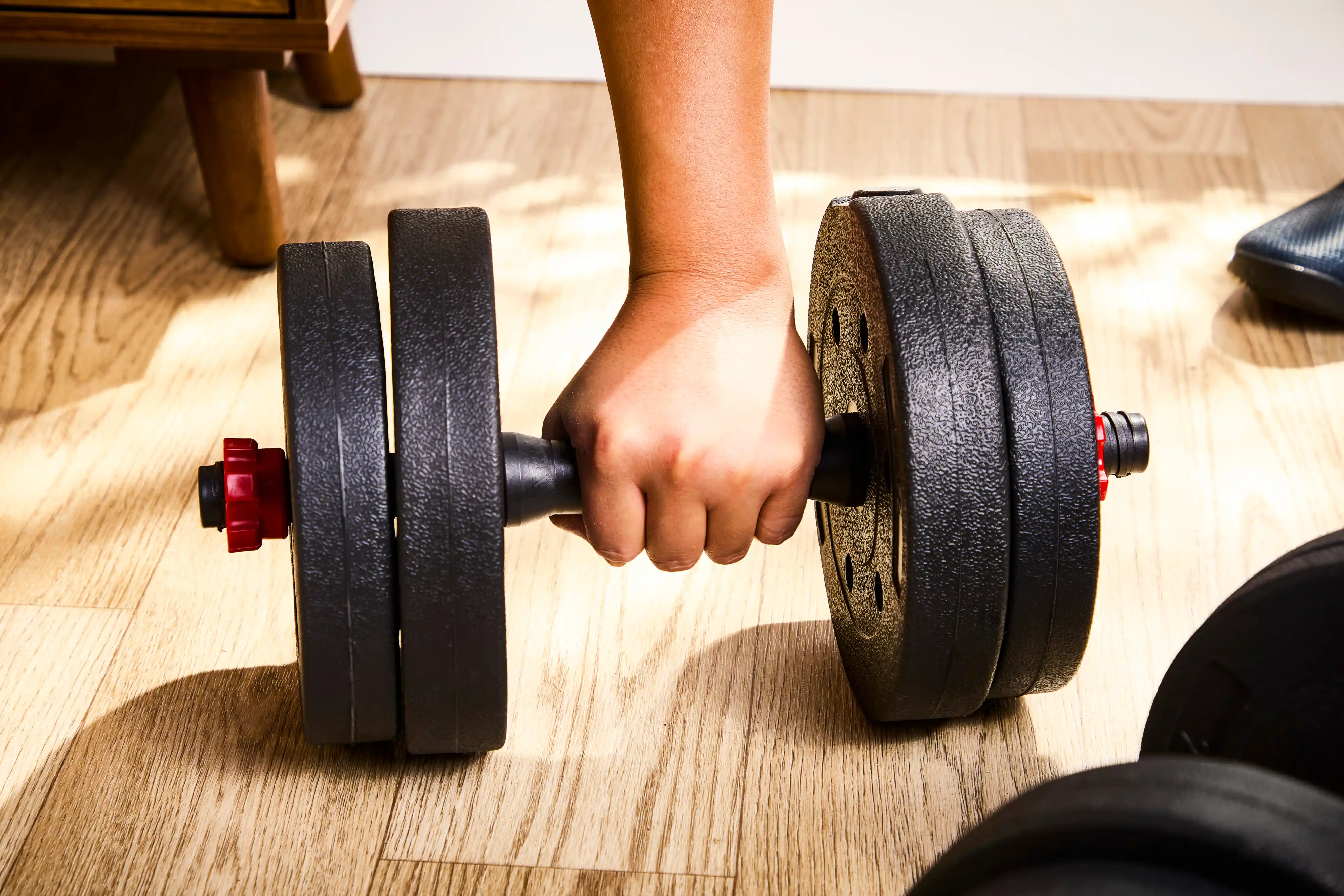 A person lifts the BCBIG Adjustable Dumbbell