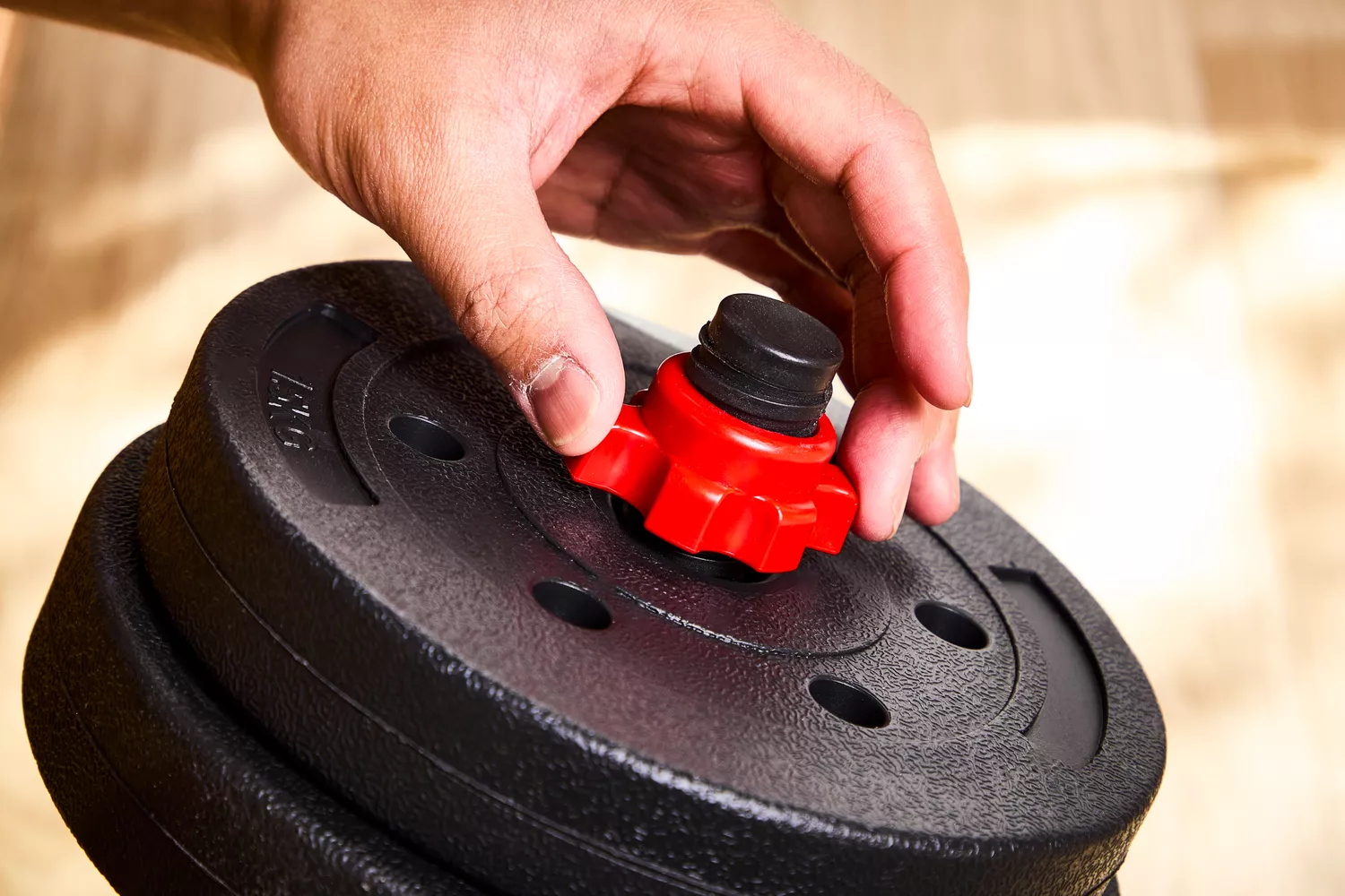 A person assembles the BCBIG Adjustable Dumbbells Set