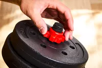 A person assembles the BCBIG Adjustable Dumbbells Set