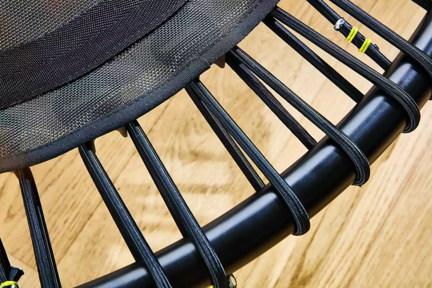 The straps of the bellicon 39 Inch Mini Trampoline up-close above a wooden floor