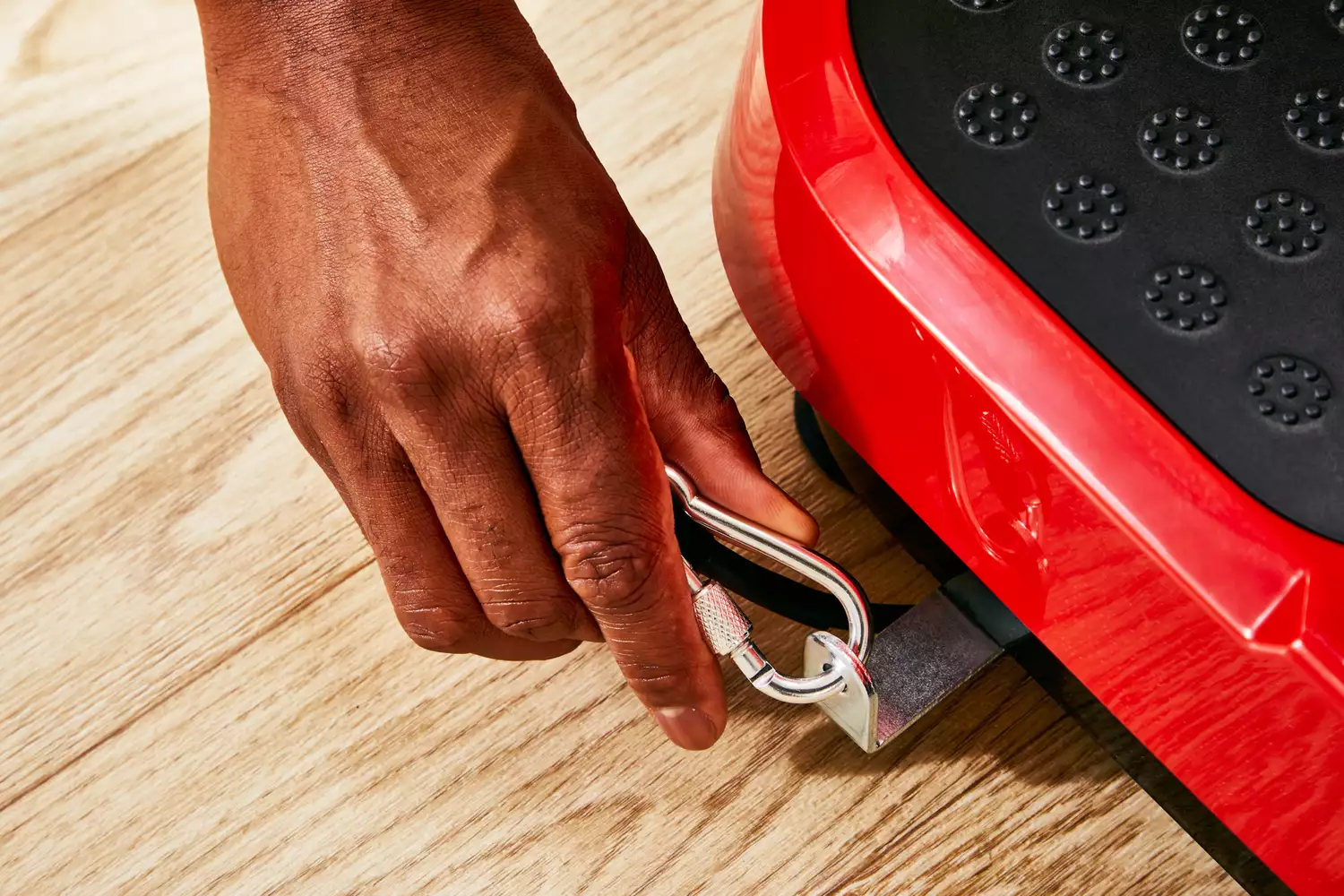 A hand clips a carabiner to the Hurtle Fitness Vibration Platform Machine