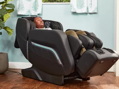 A person reclines in an iRest Zero Gravity Massage Chair in a blue room