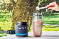 Kaged Hydra Charge jar next to a hand adding a scoop of powder into a blender bottle filled with water