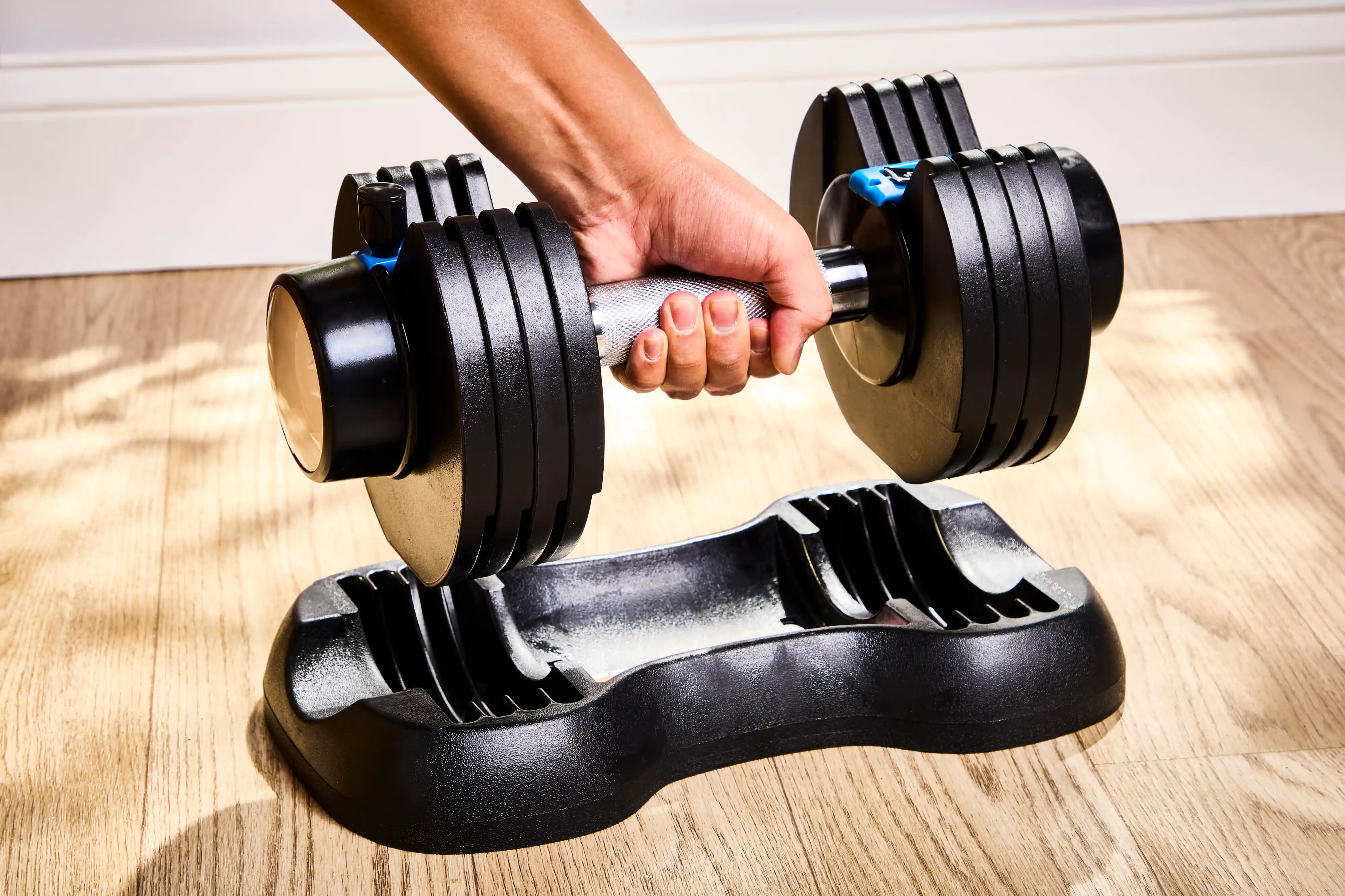 A person places the Lifepro PowerFlow Plus Adjustable Dumbbell onto its base