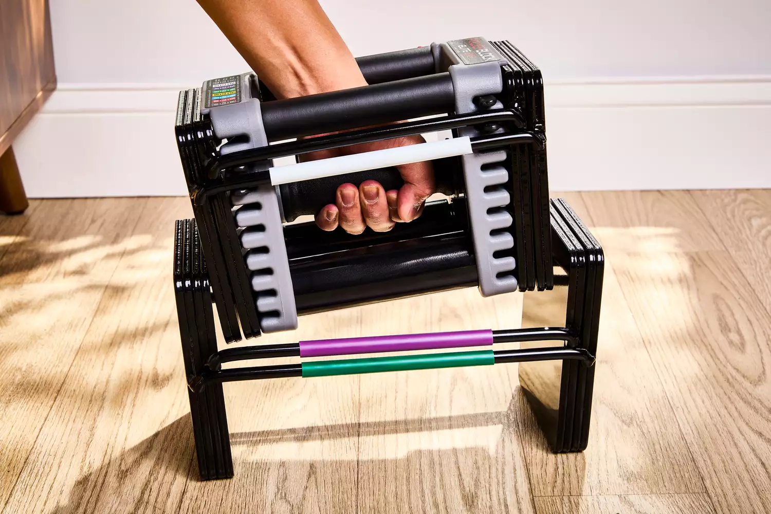 hand places the POWERBLOCK Elite EXP Adjustable Dumbbell into the base