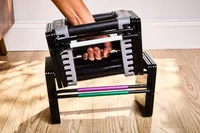 hand places the POWERBLOCK Elite EXP Adjustable Dumbbell into the base